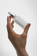 jar of cosmetics in a woman's hand, oil, serum, product with a pipette