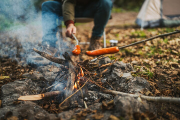 close up of sausage on wood stick grill on the camp fire