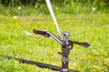 Close up of sprinkler spraying water on a field; lawn irrigation system