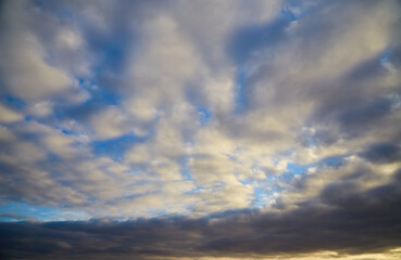 White clouds in the daytime blue sky with an approaching storm front, changing weather, heavenly background, celestial landscape.