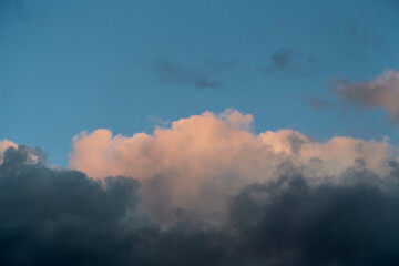 Obraz premium Gray-pink clouds in the blue sky illuminated by the setting sun in a close-up shot