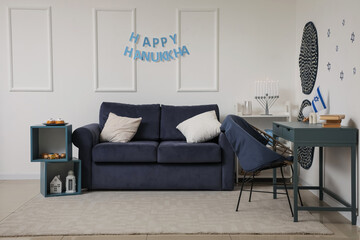 Interior of festive living room with stylish sofa, menorah and HAPPY HANUKKAH letter garland