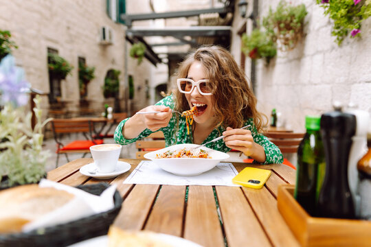 Fototapeta Woman eating italian pasta and drinking coffee at restaurant on the street in Rome. Concept of Italian gastronomy and travel.