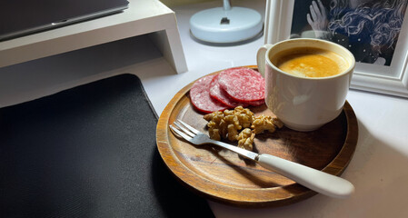 Taza de café expreso junto a nueces y salame en un escritorio, servidos para una nueva jornada de trabajo