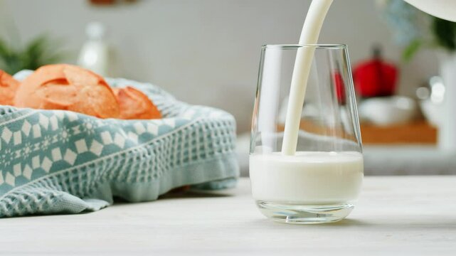 Pouring kefir yogurt into glass cup close-up. Glass with kefir or milk, lactic acid product dairy products concept. Drinking fresh lactose free in morning.