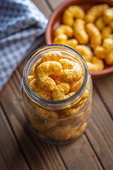 Puffed crispy Peanut flips in jar on wooden table.