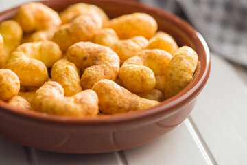 Puffed crispy Peanut flips in bowl on white table.