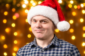 A man face, poses in New Year decorations with festive illumination and garlands, Christmas lights and decorations background, Holiday theme