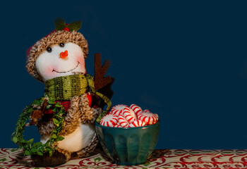 Snowman with peppermint candy on dark blue background, Christmas holiday seasonal background