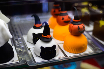 Creative Halloween-themed desserts featuring cats and pumpkins in a display case at a local bakery