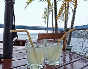 Two refreshing Mojitos on a wooden table with tropical background. Drinks concept