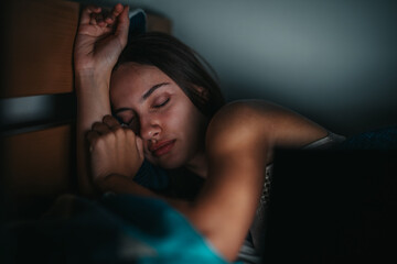 A young woman peacefully asleep, resting her head on her hand in a cozy, dimly lit bedroom. The tranquil scene captures a sense of relaxation and serenity during nighttime rest.