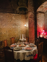 In a dimly lit room, there is a beautifully arranged table adorned with elegant plates and flickering candles that create a warm and inviting ambiance, perfect for any special occasion