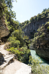 Osumi, Albania - August 15 2024: Small bridge (Ura e Vjeter e Zaberzanit) crossing the Osumi River Canyon. Beautiful views on famous gorge and river.