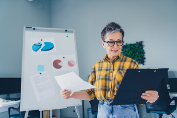Photo of nice retired woman paperholder papers trading wear plaid shirt comfortable modern office loft room interior indoors workspace