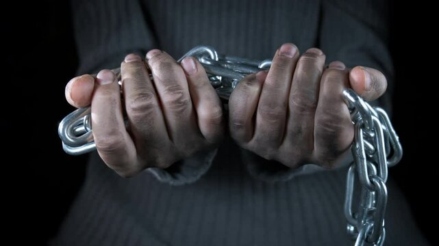 Slave hands in chain. A view of abandoned slave dirty hands chained against black background.