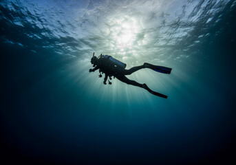 A diver explores deep ocean waters beneath a bright sunlit surface on a tranquil underwater adventure