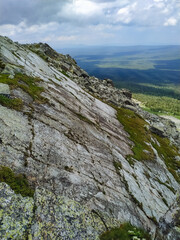 A majestic and towering mountain, beautifully adorned with rugged rocks and patches of lush green grass, creates a truly stunning and captivating natural landscape that inspires awe