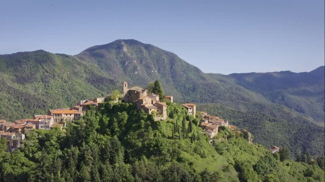 Mountain Village Chuch in Liguria: Drone View of Italy&rsquo;s Green Hills and Mountain Panorama on a Bright Day with Blue Sky &ndash; Close Up Drone Flyover Tracking Left