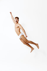 Fototapeta premium Energetic young man jumping excitedly against a white background, expressing joy and freedom. A representation of youthful exuberance and playful spirit.