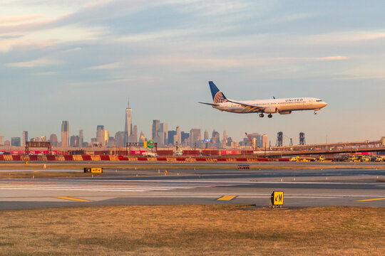 Newark Liberty Airport, Newark, New Jersey, USA - October 31, 2024 - United Airlines Jet landing at Newark Liberty Airport at golden hour with the Lower Manhattan skyline in the background