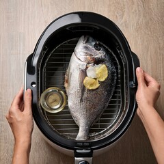 hand cooking a gilthead sea bream whole fish recipe in air fryer in the kitchen top view