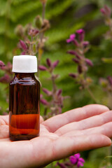 Small Amber Glass Bottle Held in Hand Outdoors