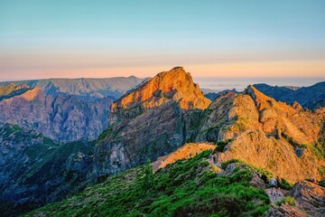 Pico de Arieiro, Madeira - A picturesque view of the mountains illuminated by the warm light of sunset. The rugged terrain features winding trails where hikers explore the stunning landscape.