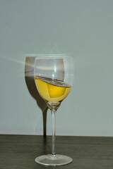 A glass of yellow liquid reflecting light beautifully against a simple background