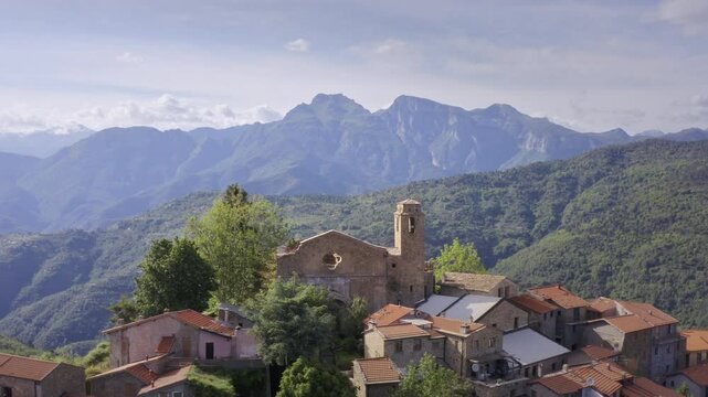 Mountain Village in Liguria: Drone View of Italy&rsquo;s Green Hills and Mountain Panorama on a Bright Day with Blue Sky &ndash; Close Up Drone Flyover Tracking Left