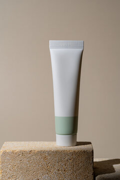 Modern cosmetic tube on stone podium with shadow