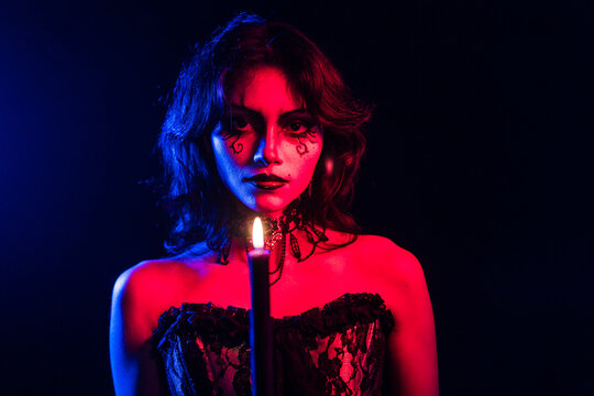 Mysterious Gothic Woman with Candle in Red and Blue Lighting