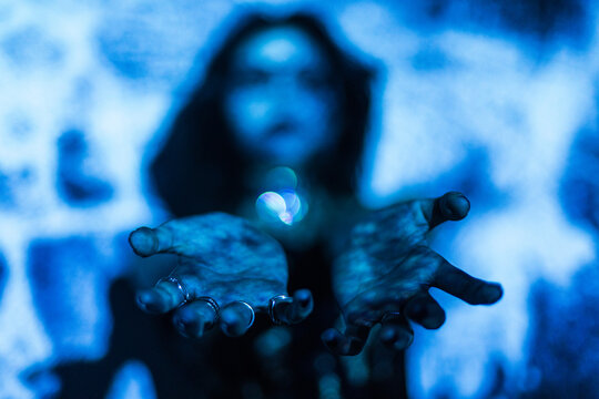 Gothic woman with outstretched hands in eerie blue light