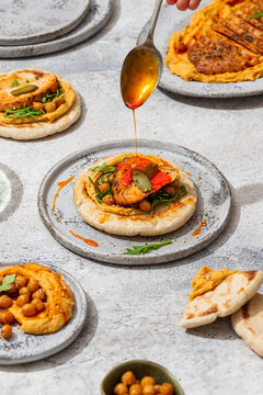 Top view of colorful roasted chicken on hummus with herbs