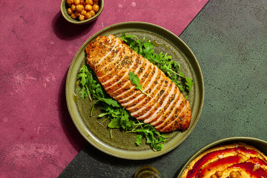 Sliced roasted turkey breast with arugula on rustic plate