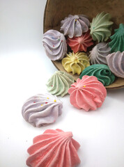 Close up of meringue cookies spilling out of wooden bowl with selective focus
