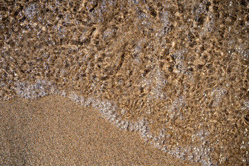 Texture of sand and water on the beach close-up.
