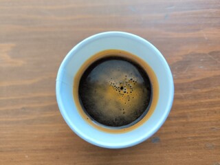 A small glass of espresso coffee on a table and in overhead view