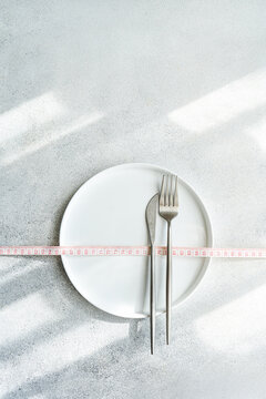 Minimalist diet concept with plate and measuring tape