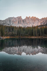 Dolomitic mountains and trees perfectly mirrored into the famous italian Lake Carezza