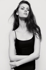 Elegant young woman with long hair posing confidently in a fitted black top, showcasing beauty and grace against a minimalist white background.