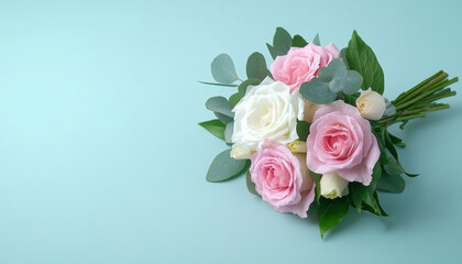 A beautiful bouquet of pink and white roses, complemented by greenery, rests on a soft mint background, ideal for celebrations or decor.