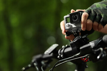 Man with modern action camera on bicycle outdoors, closeup. Space for text