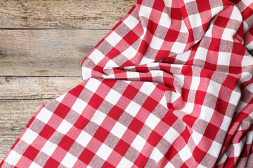 Obraz premium Crumpled tablecloth with checkered pattern on wooden table, top view
