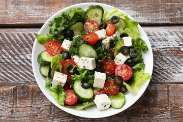 Delicious salad with feta cheese on wooden table, top view