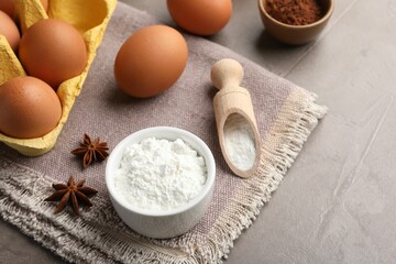 Baking powder, anise stars, eggs and cocoa on grey textured table, closeup