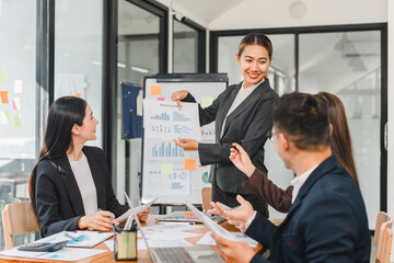 Professional business meeting with woman presenting marketing data to colleagues. team is engaged, discussing strategies and analyzing charts in modern office setting