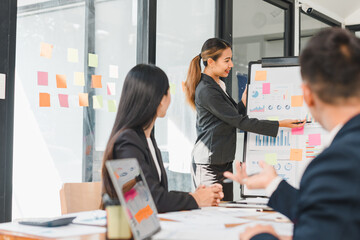 Efficient business meeting with woman presenting data on board, while colleagues engage. atmosphere is focused and collaborative, showcasing teamwork and professionalism