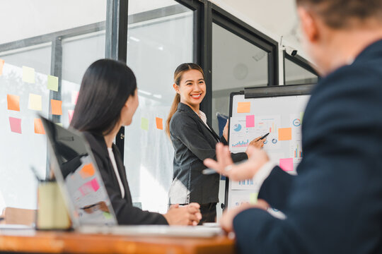 Business meeting with confident woman presenting data to colleagues, showcasing teamwork and collaboration in modern office setting