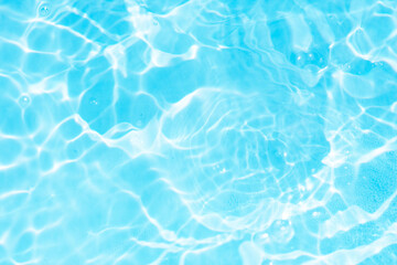 Blue water with ripples on the surface. Defocus blurred transparent blue colored clear calm water surface texture with splashes and bubbles. Water waves with shining pattern texture background.